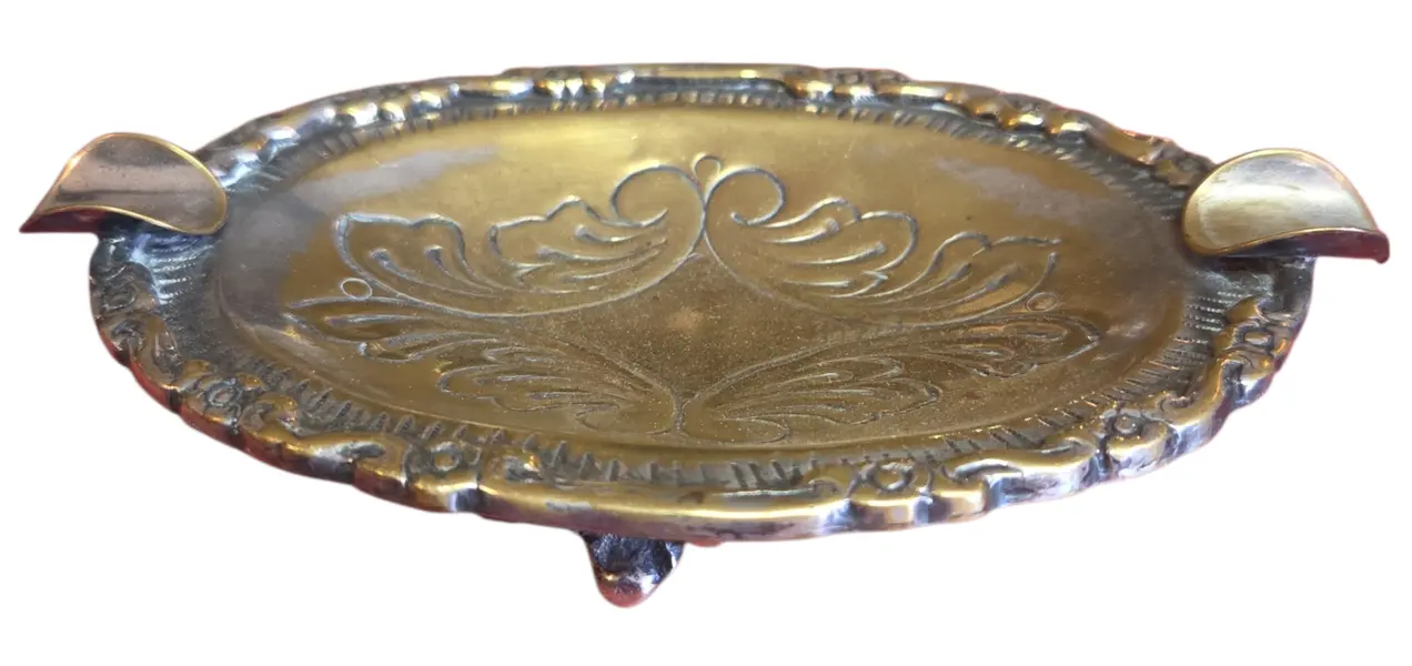 Foto de um(a) Cinzeiro Ornamentado em Metal, da categoria de Cinzeiros. Uma peça que exala sofisticação e história. Este cinzeiro oval em metal apresenta um rico trabalho de ornamentação, com... Vendido no marketplace Trésors.