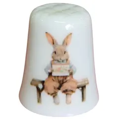 Foto de um(a) Dedal de Coleção em Porcelana - Estampa Casal de Coelhos e Coelhinho no Banco, da categoria de Outros colecionáveis. Este é um delicado dedal colecionável em porcelana branca, que apresenta uma temática lúdica e clássica de "Easter Bunnies"... Vendido no marketplace Trésors.