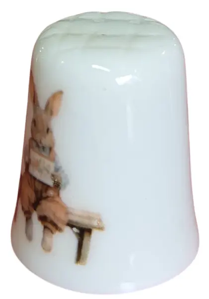 Foto de um(a) Dedal de Coleção em Porcelana - Estampa Casal de Coelhos e Coelhinho no Banco, da categoria de Outros colecionáveis. Este é um delicado dedal colecionável em porcelana branca, que apresenta uma temática lúdica e clássica de "Easter Bunnies"... Mostrado de uma perspectiva diferente. Vendido no marketplace Trésors.