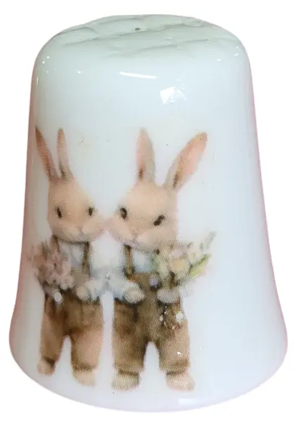 Foto de um(a) Dedal de Coleção em Porcelana - Estampa Casal de Coelhos e Coelhinho no Banco, da categoria de Outros colecionáveis. Este é um delicado dedal colecionável em porcelana branca, que apresenta uma temática lúdica e clássica de "Easter Bunnies"... Mostrado de uma perspectiva diferente. Vendido no marketplace Trésors.