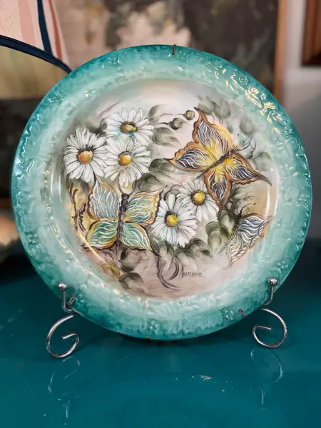 Foto de um(a) Prato de parede pintado à mão, da categoria de Pratos Decorativos. Prato de parede em porcelana, pintado à mão, assinado. Mostrado de uma perspectiva diferente. Vendido no marketplace Trésors.