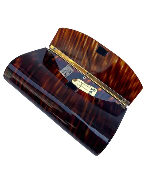 Foto de um(a) Clutch Vintage de Mão Ika, da categoria de Bolsas. Bolsa de mão vintage, marca Ika, padrão tartaruga, em lucite, acrílico, ferragem em metal, fecho em velcro, não possui alça,... Mostrado de uma perspectiva diferente. Vendido no marketplace Trésors.