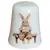 Foto de um(a) Dedal de Coleção em Porcelana - Estampa Casal de Coelhos e Coelhinho no Banco, da categoria de Outros colecionáveis. Este é um delicado dedal colecionável em porcelana branca, que apresenta uma temática lúdica e clássica de "Easter Bunnies"... Vendido no marketplace Trésors.
