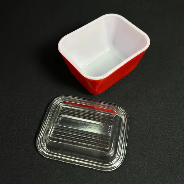 Foto de um(a) Manteigueira Pyrex Opalina Americana, da categoria de Outros utensílios para servir. Fantástico recipiente em opalina da pirex, made USA, parte externa na cor vermelha, tampa em vidrão incolor. Originalmente... Mostrado de uma perspectiva diferente. Vendido no marketplace Trésors.
