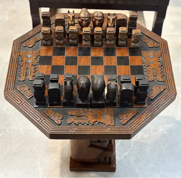 Foto de um(a) Mesa de Xadrez Entalhada, da categoria de Mesas de centro. Antiga mesa de xadrez, base em escultura de totem asteca entalhado em monobloco de carvalho, tampo oitavado com inscrições... Mostrado de uma perspectiva diferente. Vendido no marketplace Trésors.